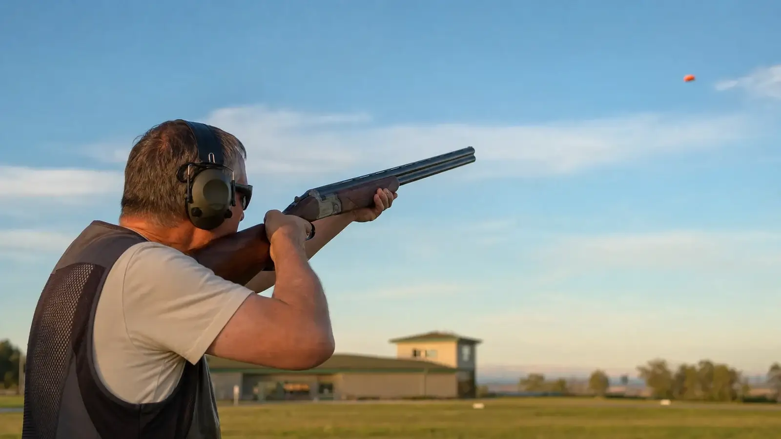 Tireur de skeet brisant un plateau d'argile lancé sur le parcours