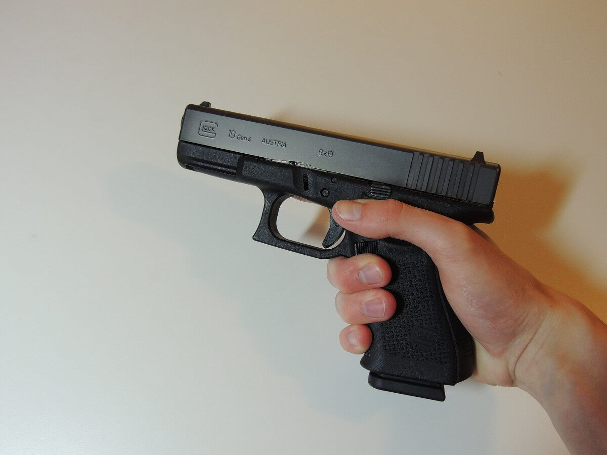 Glock 19 Gen 4 tenu en main, poignée et pontet visibles