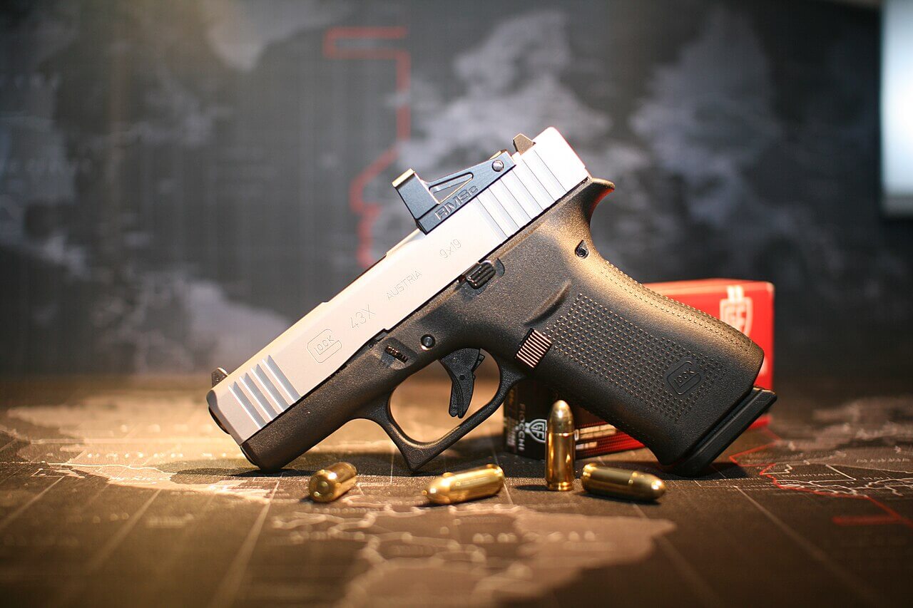 Glock 43X à culasse argent équipé d'un point rouge, avec des cartouches 9x19