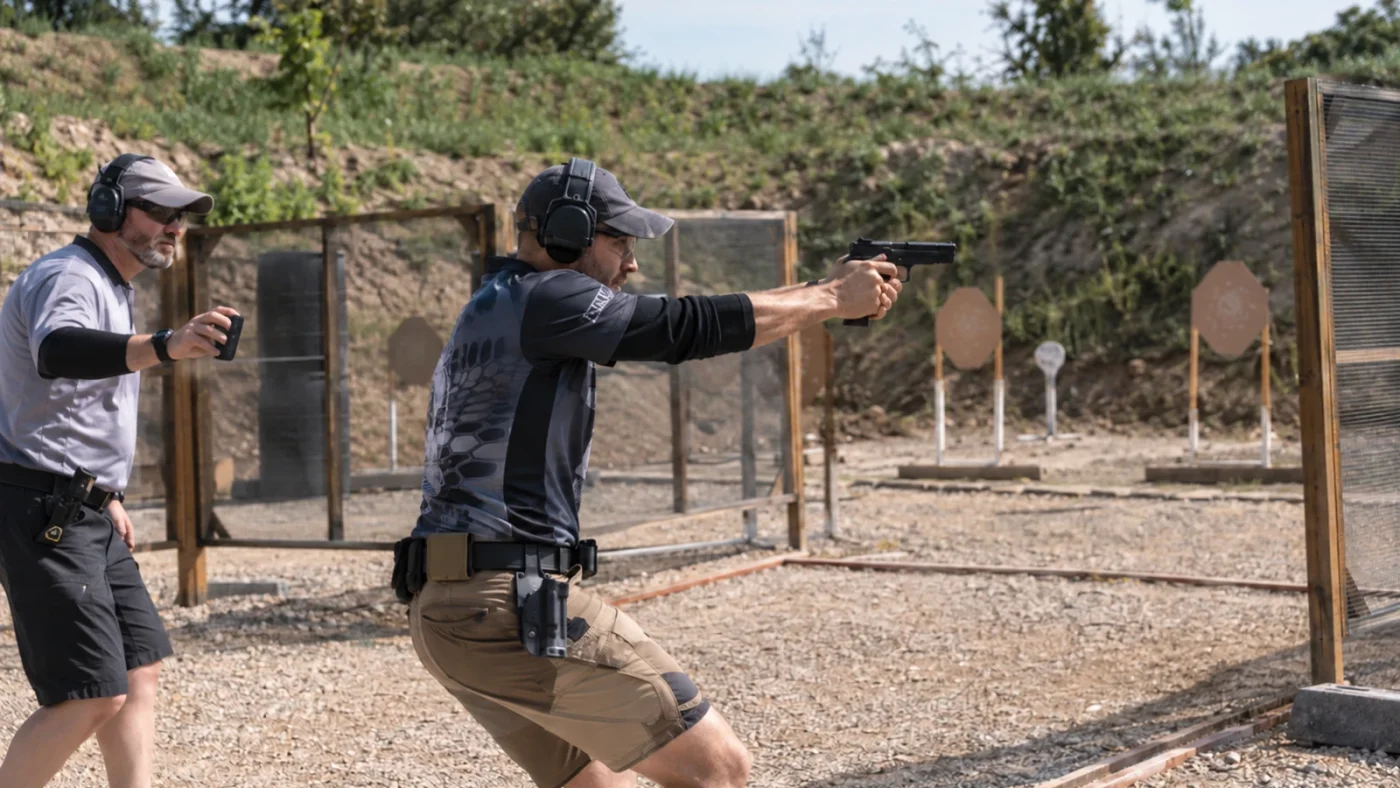 Tireur au pistolet engagé sur un parcours IPSC sous le contrôle d’un arbitre