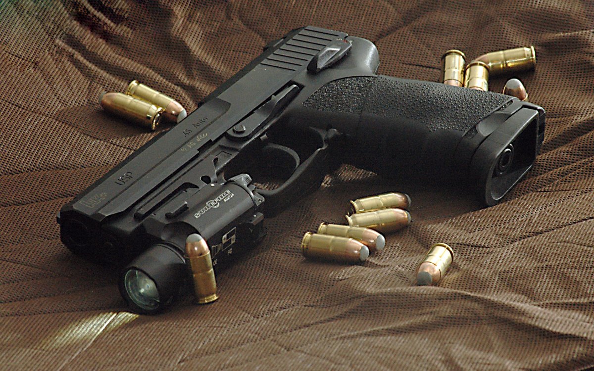 Heckler & Koch USP en .45 ACP équipé d'une lampe tactique, cartouches .45 autour